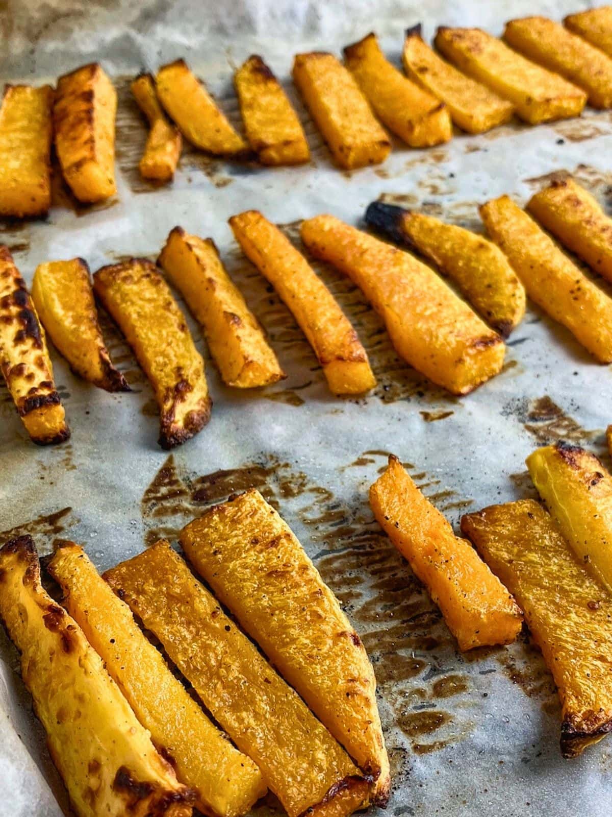 Oven baked butternut squash fries on a baking sheet.