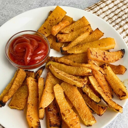 Easy homemade butternut squash fries on a plate with ketchup dip.