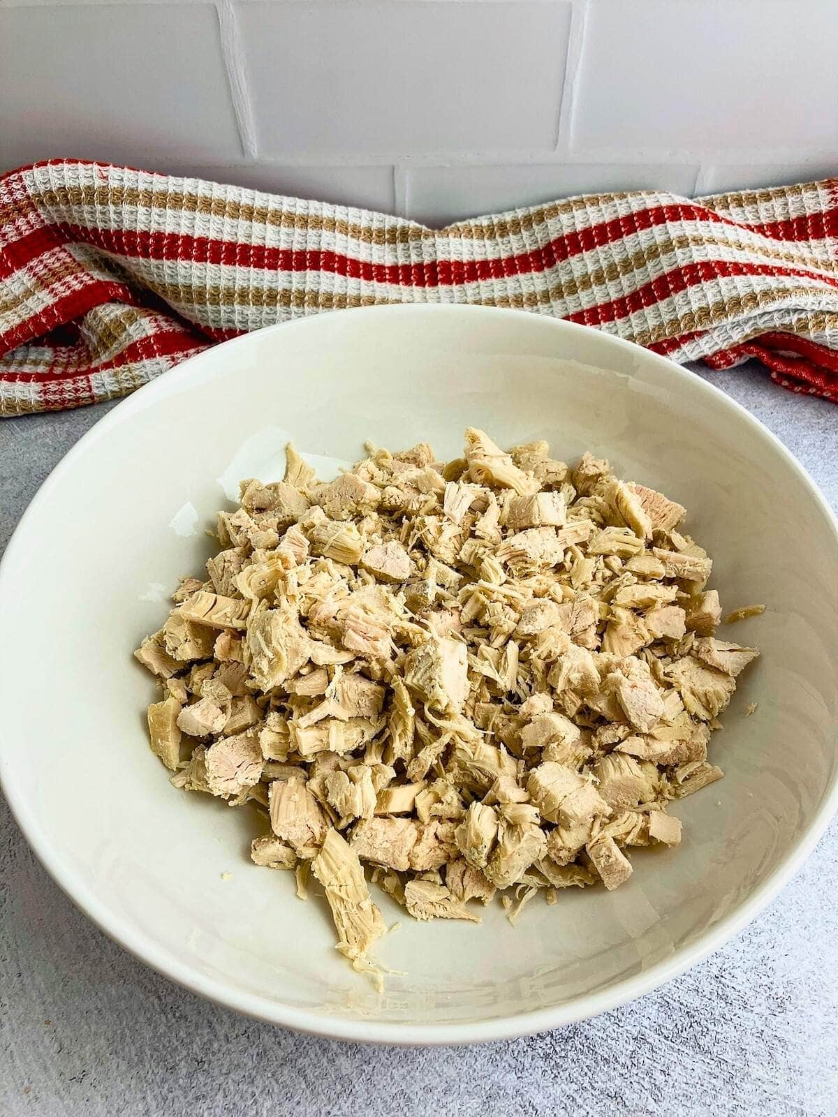 Diced cooked chicken in a large white bowl.
