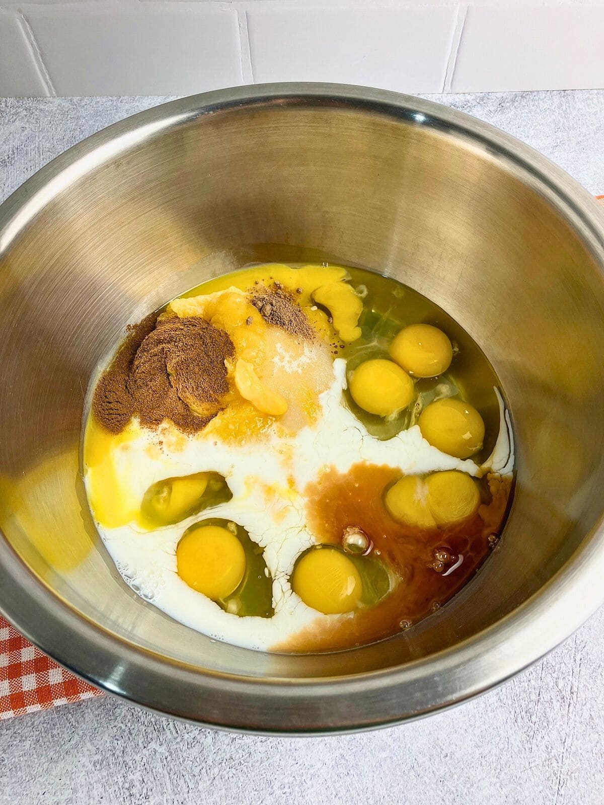 Eggs, spices, vanilla, and milk in a large mixing bowl.