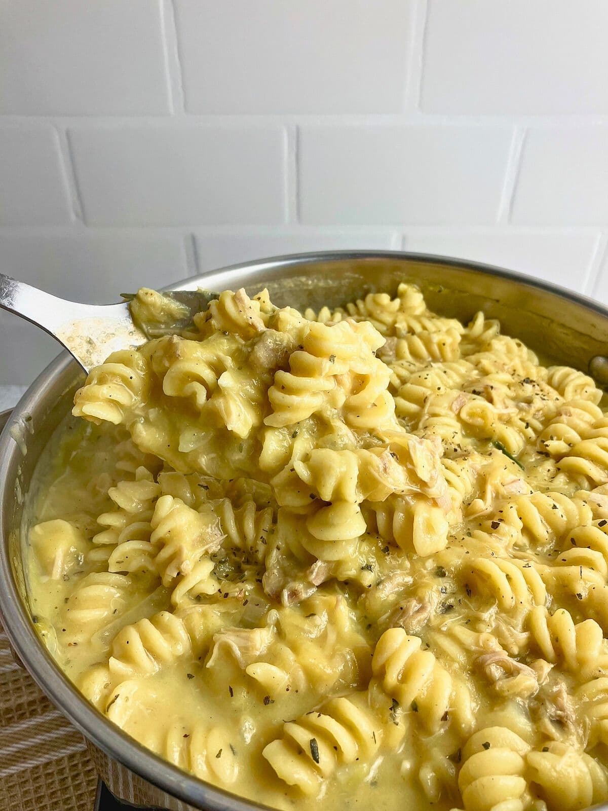 A spoonful of turkey pumpkin pasta held up over the pot.