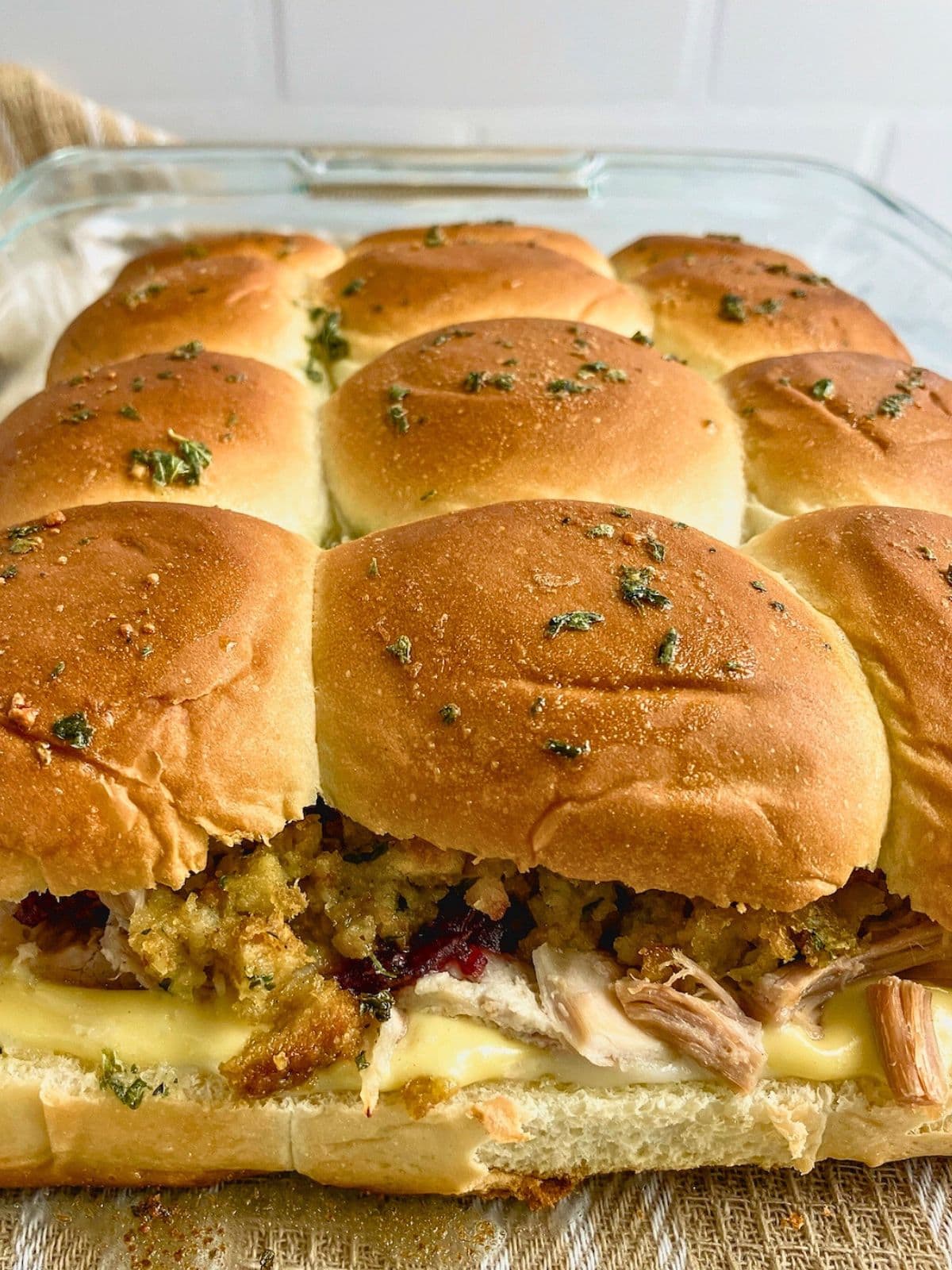 Leftover turkey sliders warm from the oven in a glass baking dish.