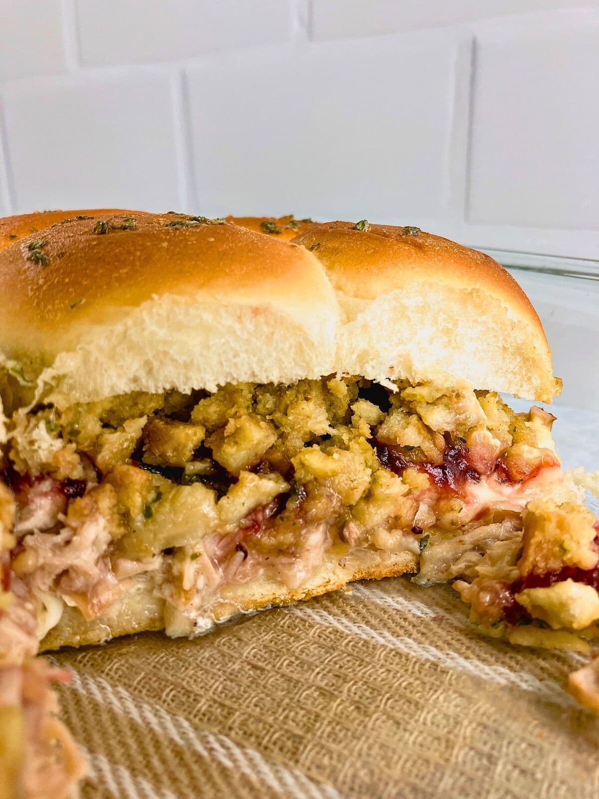 Turkey sliders in a baking dish with some sliders removed.