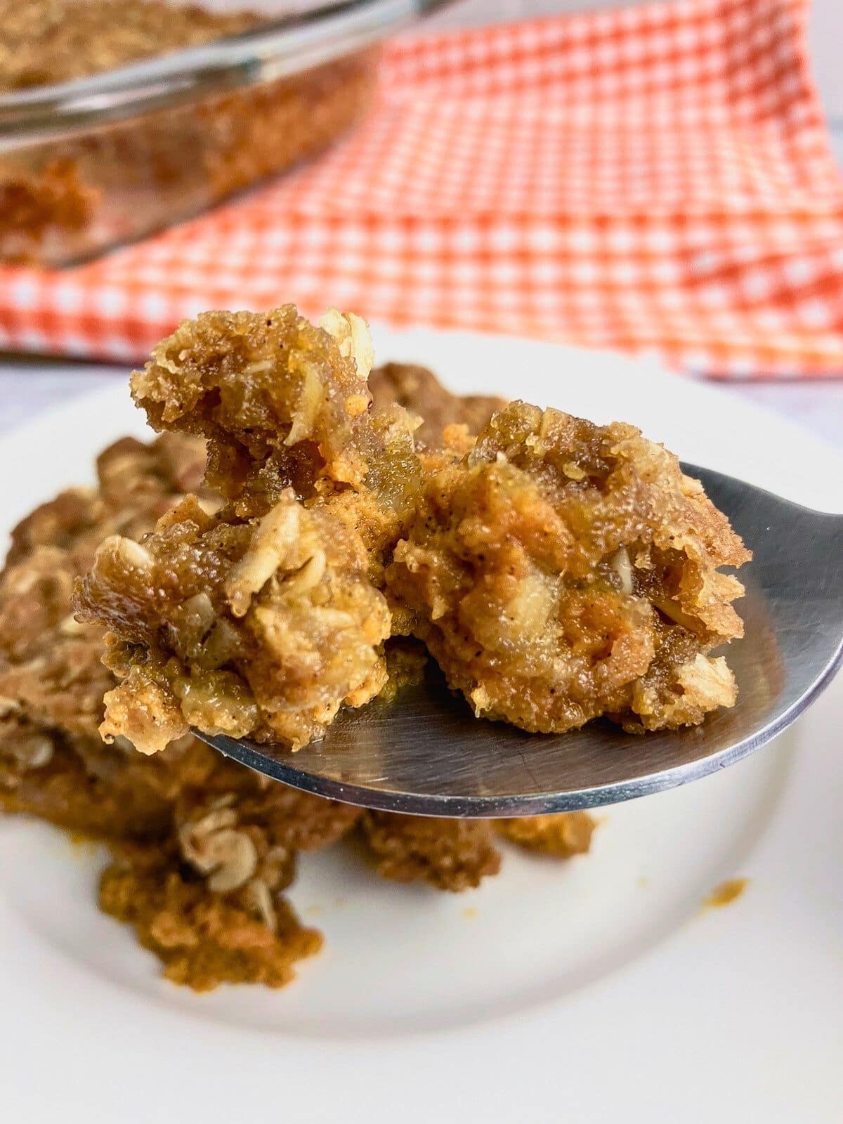 A spoonful of pumpkin crisp is being held up.