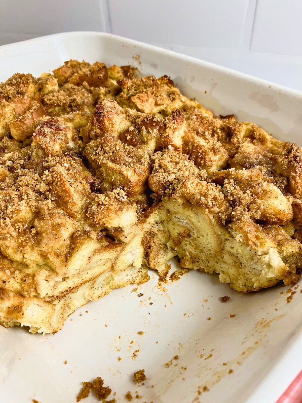 A baking dish of pumpkin French toast casserole with a slice removed.