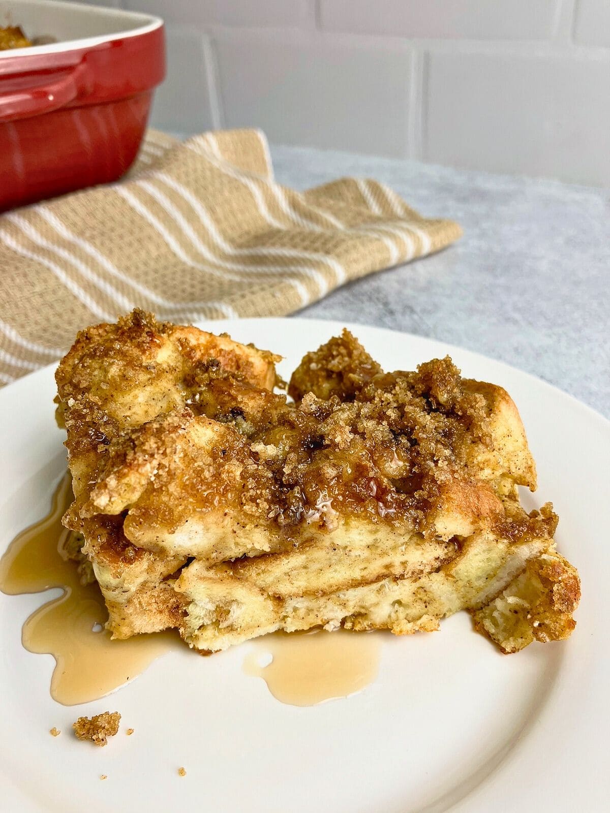 French toast pumpkin casserole with a brown sugar topping on a plate and drizzled with maple syrup.