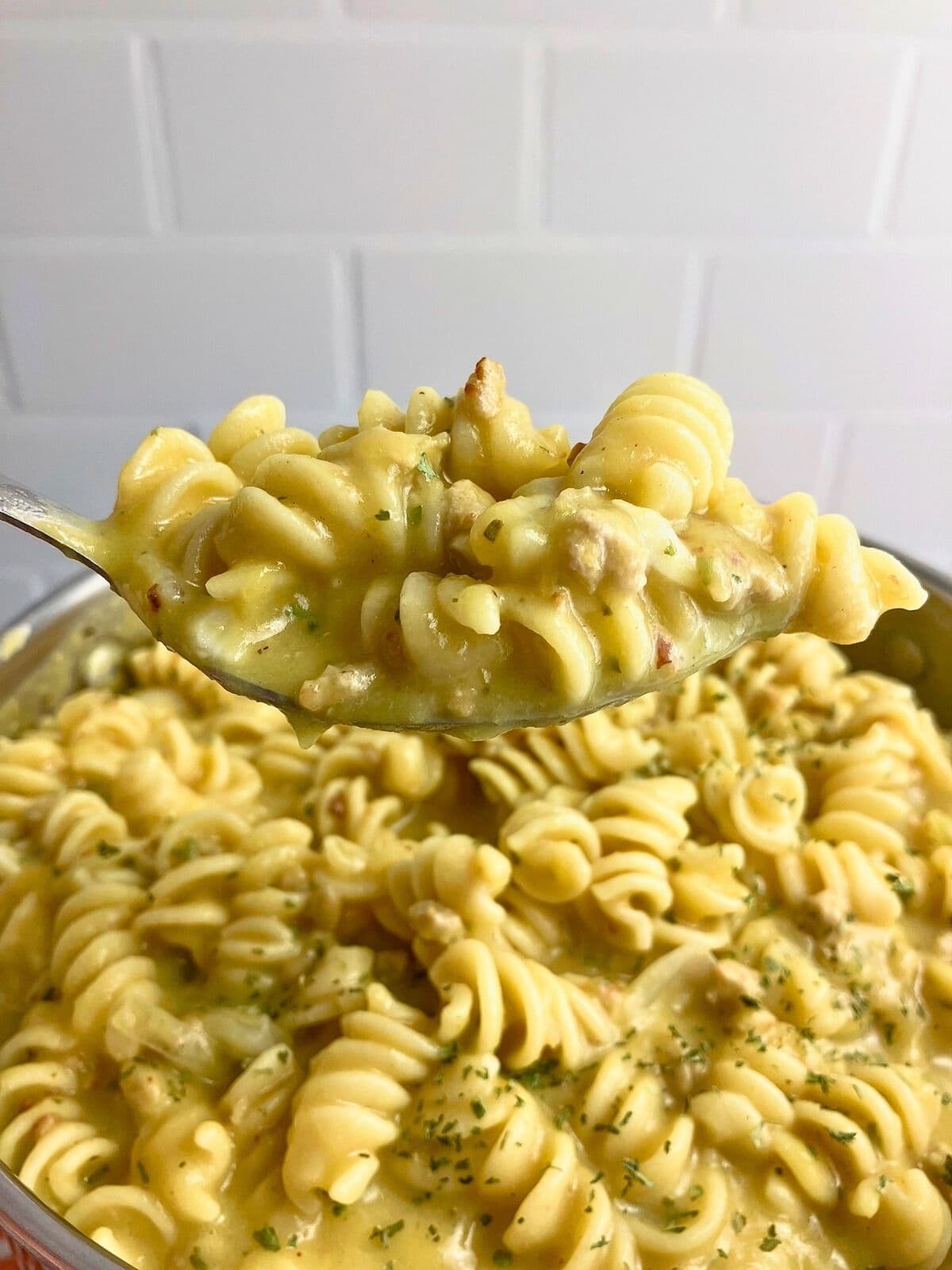 Holding up a spoonful of pumpkin pasta over the pot.