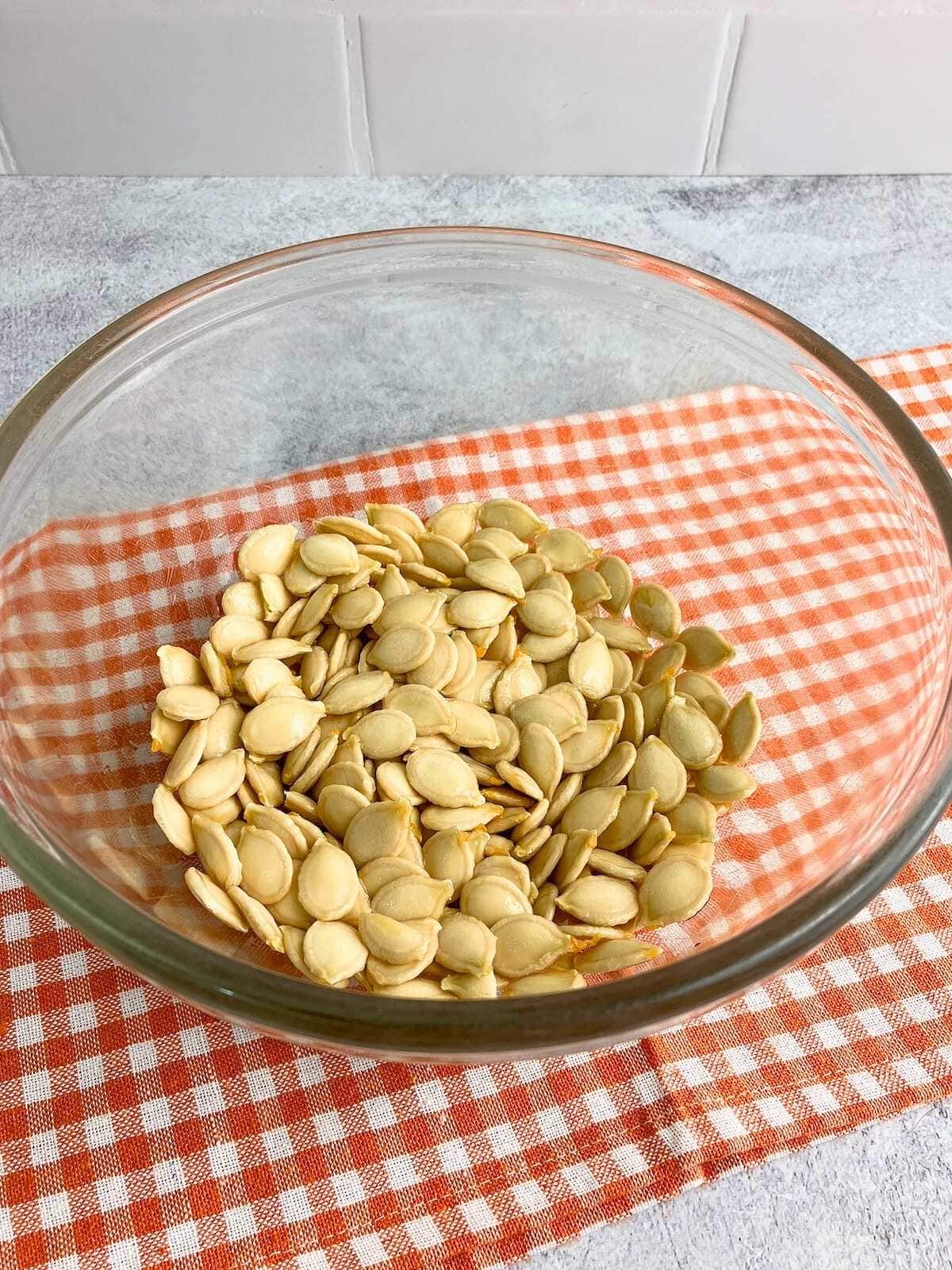 Cleaned, raw pumpkin seeds in a mixing bowl.