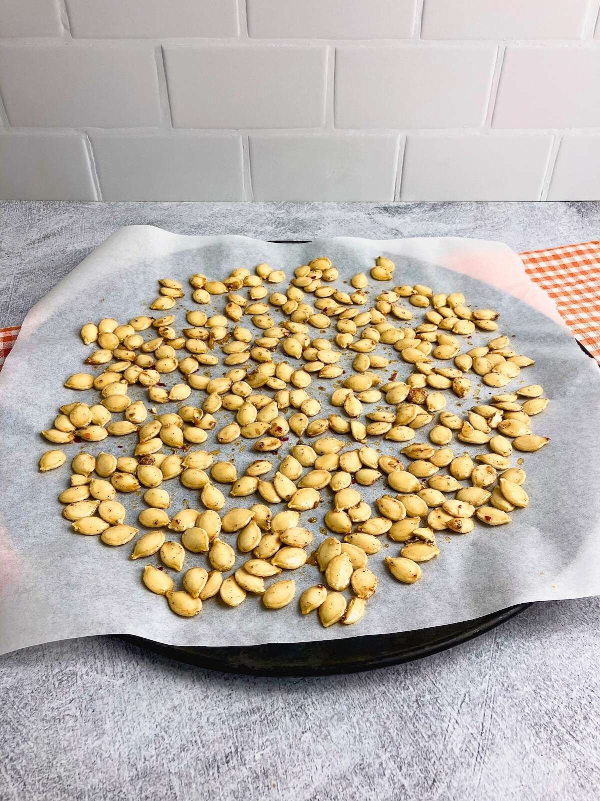 Raw seasoned pumpkin seeds on a baking tray.
