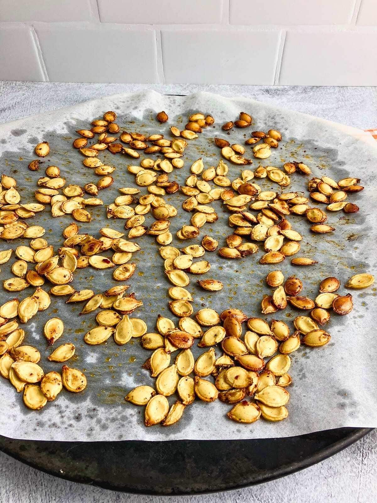 Spicy roasted pumpkin seeds on a baking tray.
