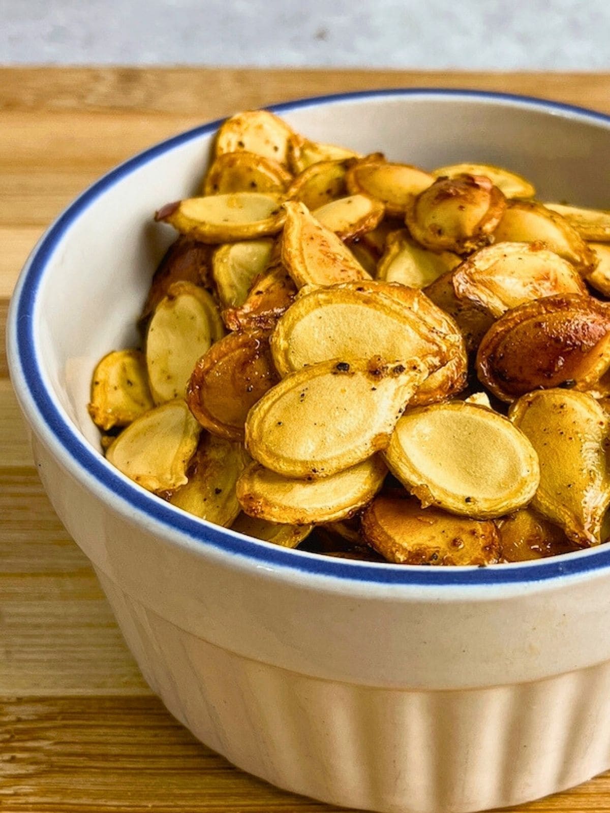 Homemade spicy roasted pumpkin seeds in a small white bowl.