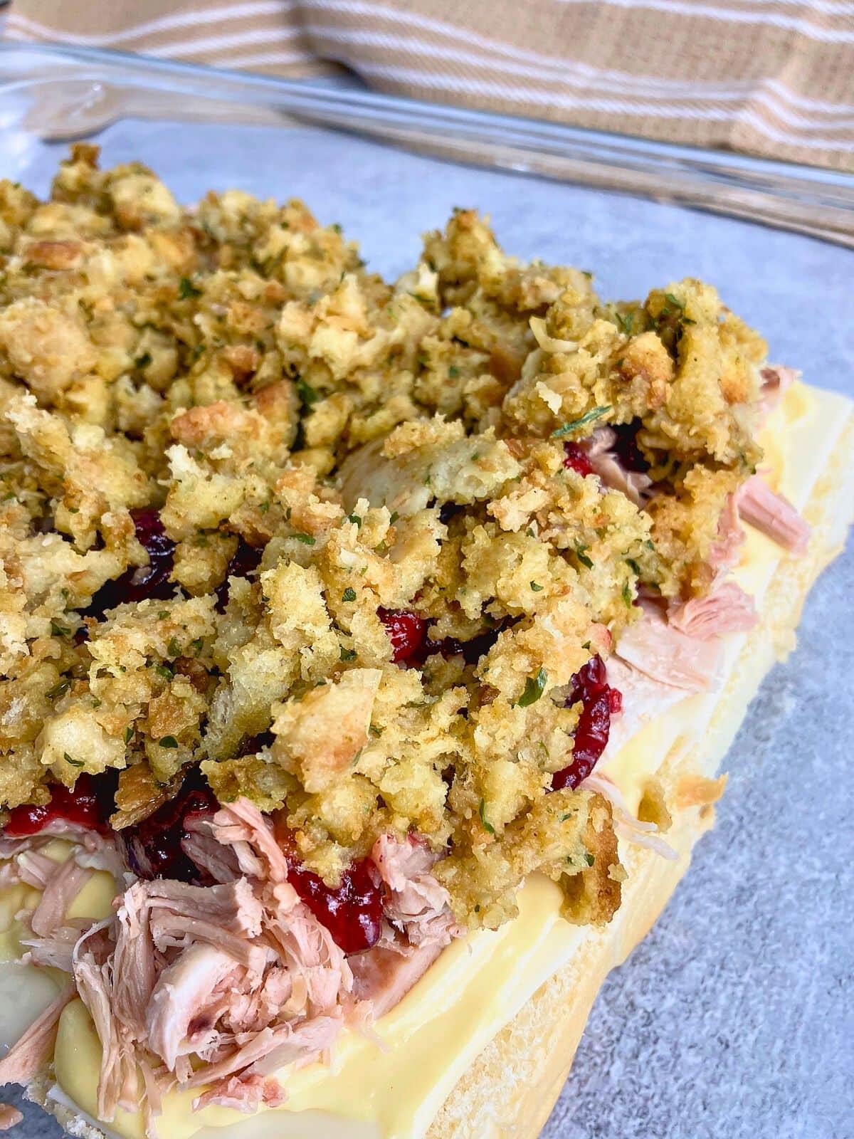 The stuffing layer is spread over the cranberry sauce.