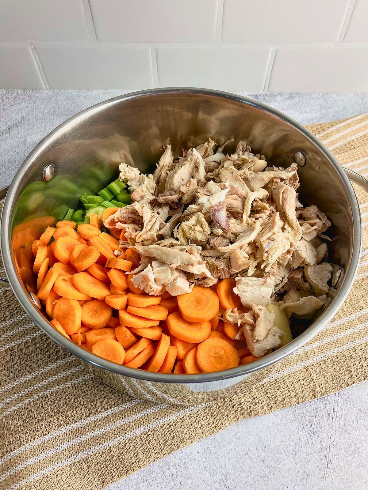 A large stock pot filled with sliced veggies and cooked turkey.