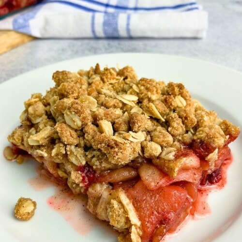 A slice of homemade apple cranberry crisp on a white plate.