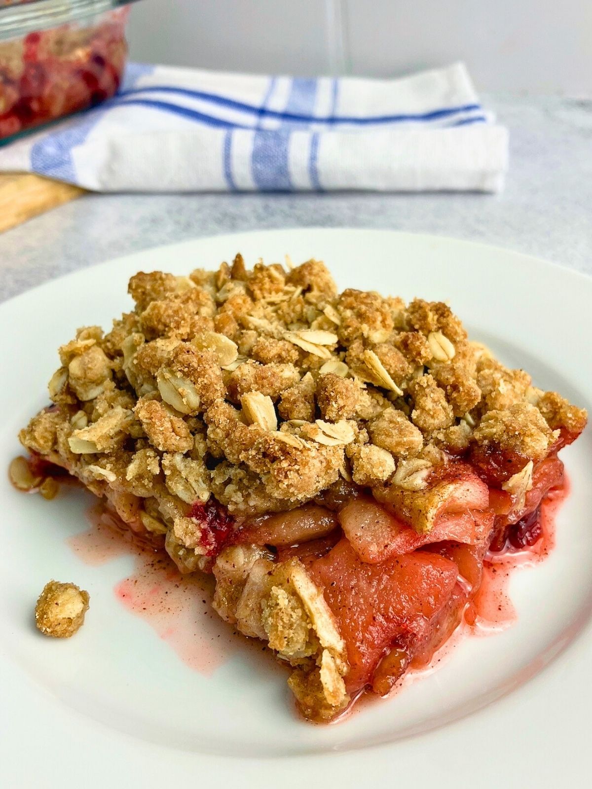 A slice of homemade apple cranberry crisp on a white plate.