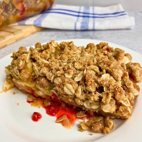 Homemade apple cranberry pumpkin crisp on a white plate.