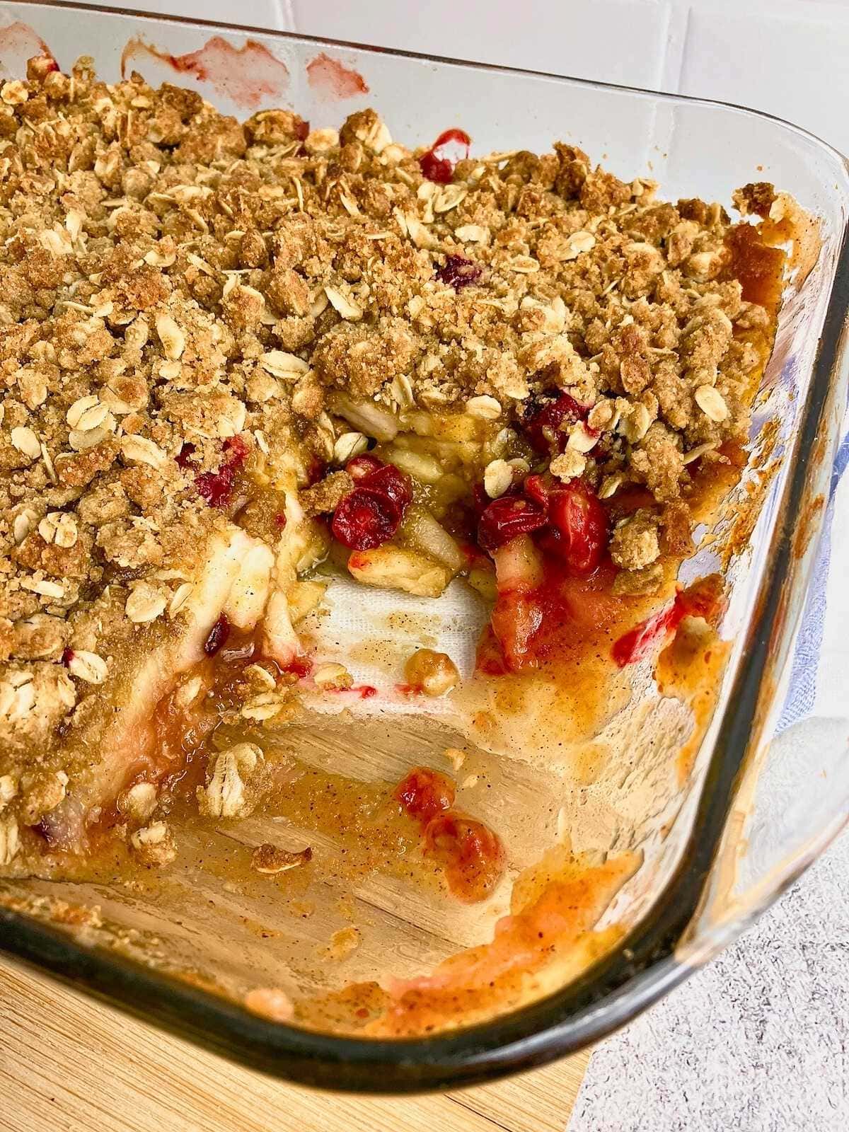 A slice removed from the baking dish of cranberry apple pumpkin crisp.