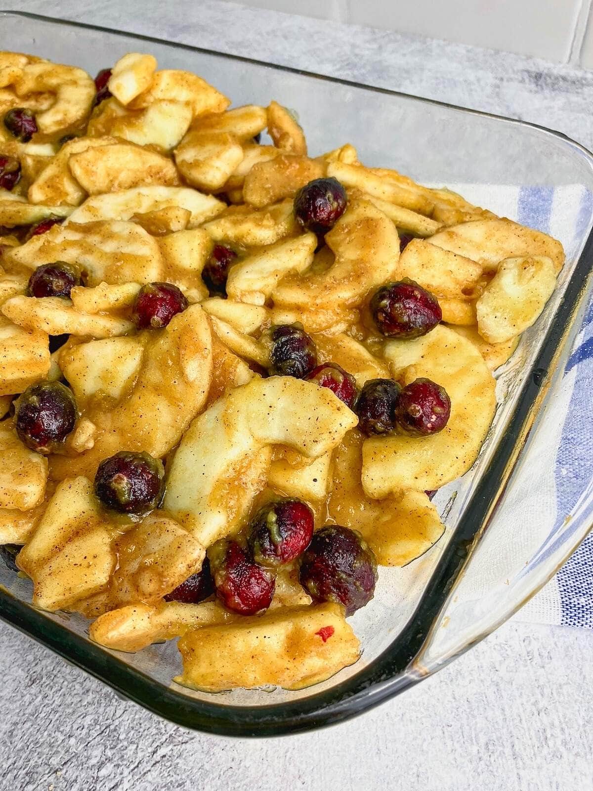 Apple, cranberry, and pumpkin mixture spread into a baking dish.
