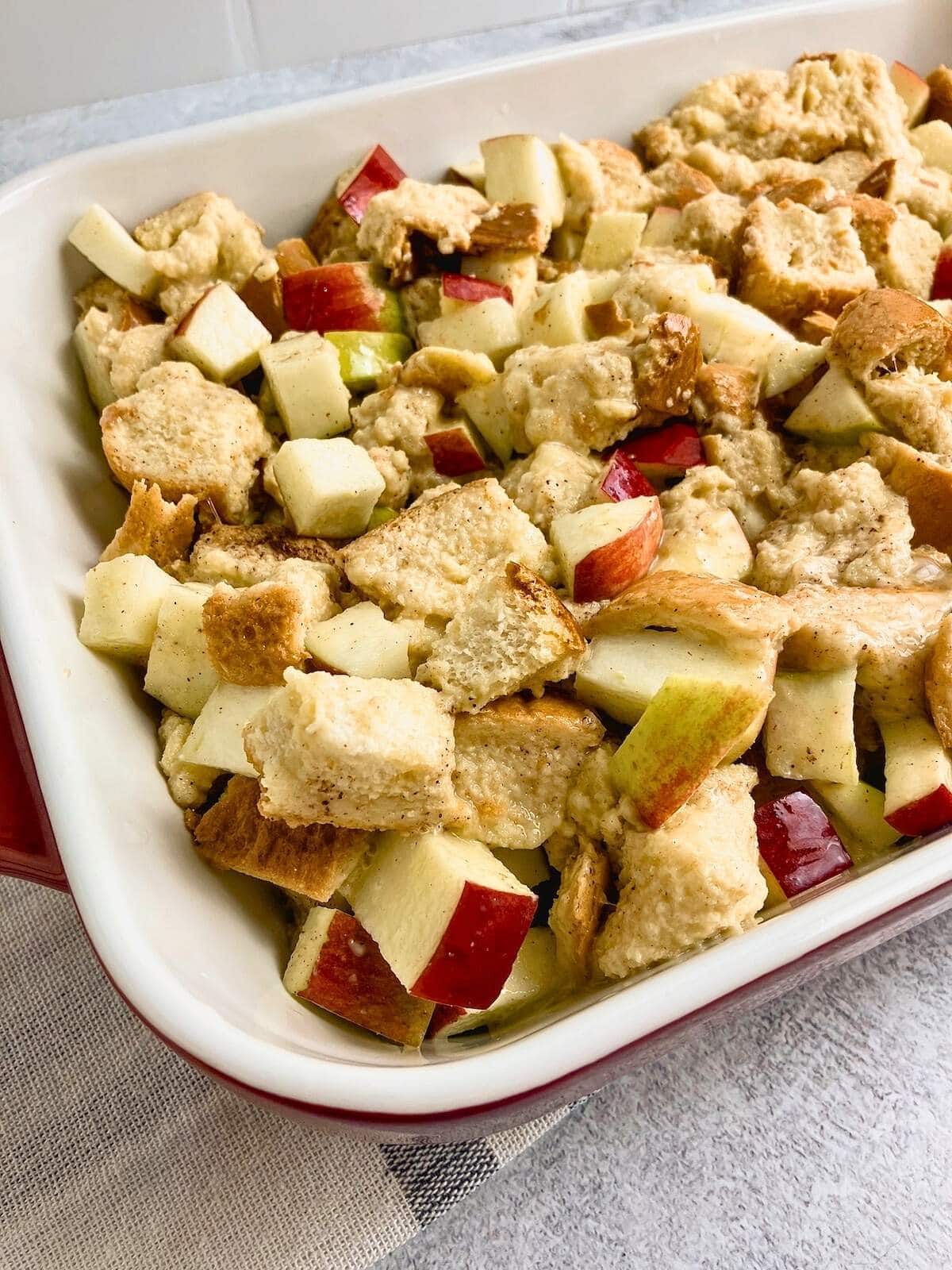 Bread and apple mixture spread into a baking dish.