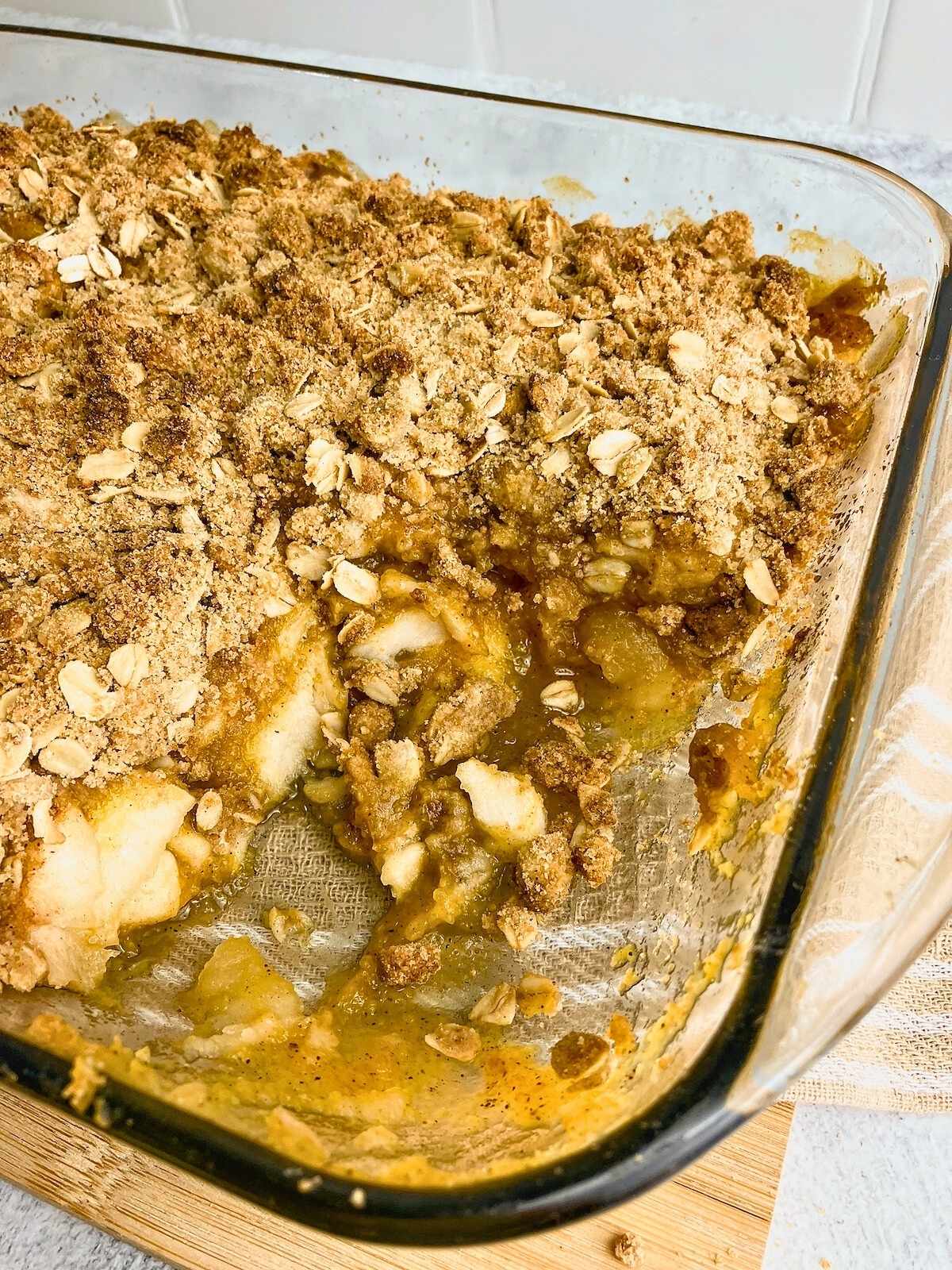 A 9x13 glass baking dish of pumpkin apple crisp with a slice removed.