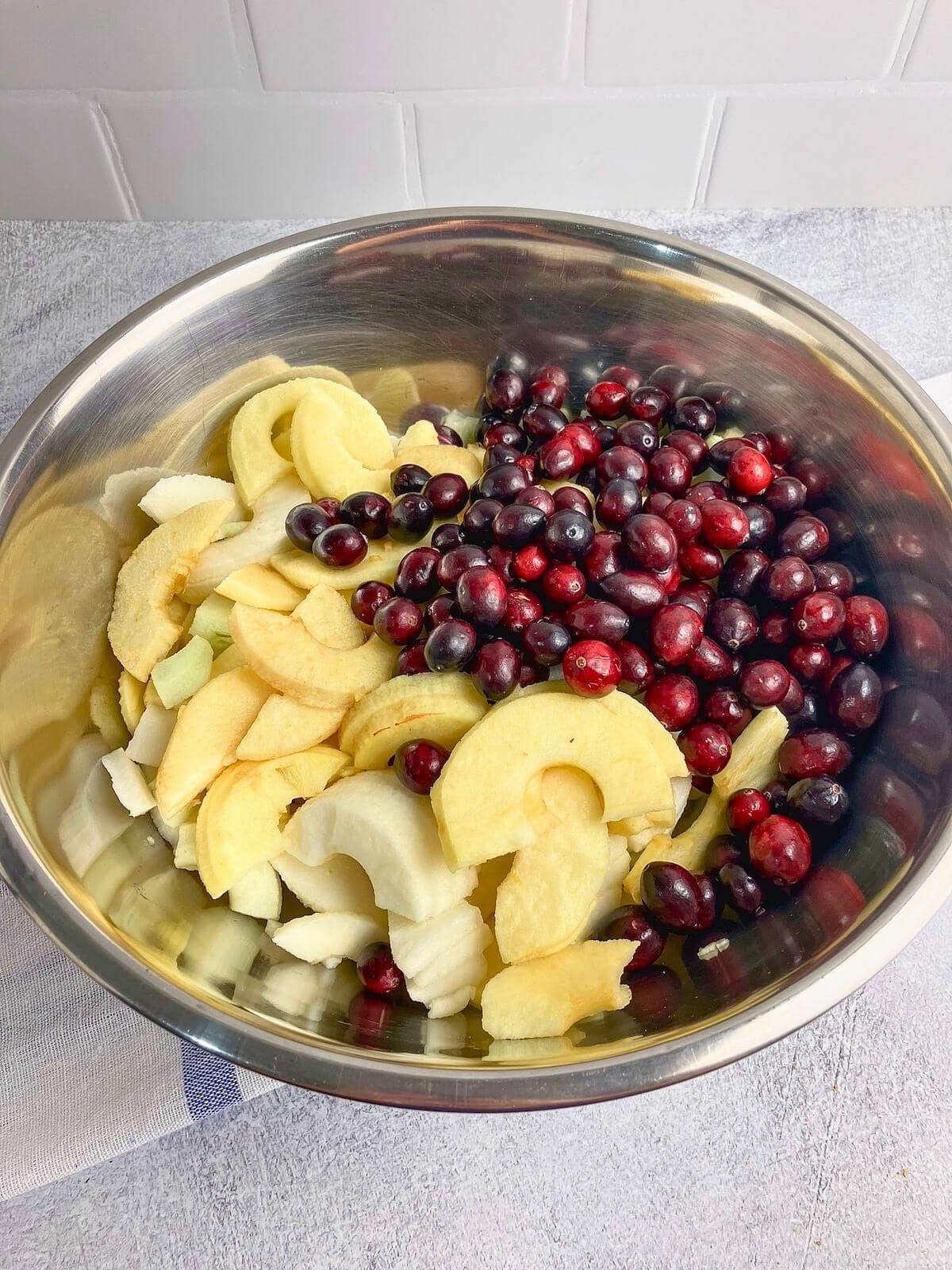 Peeled and sliced apples and cranberries in a large mixing bowl.