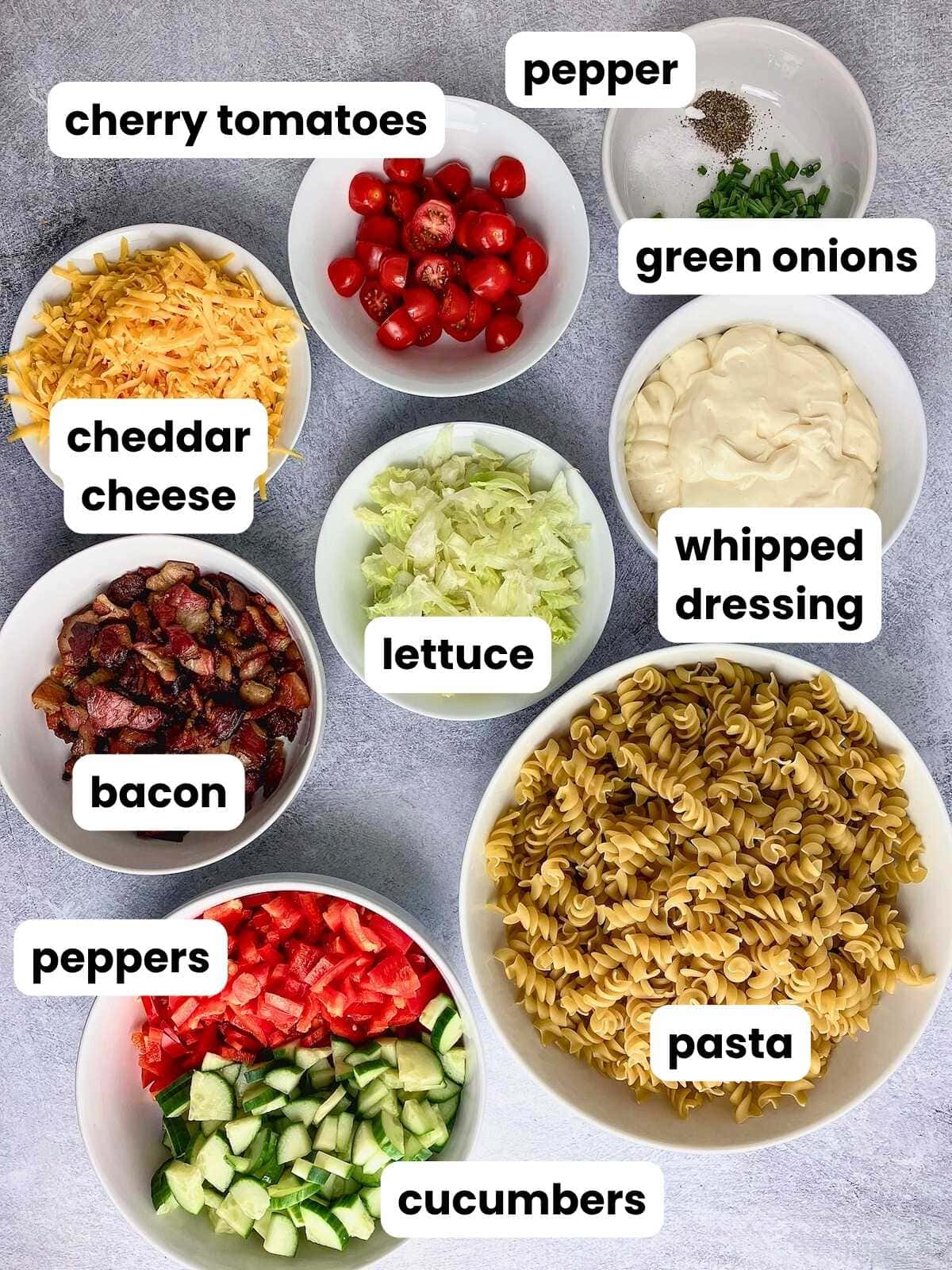 Ingredients for the bacon pasta salad are in ingredient bowls on the counter.