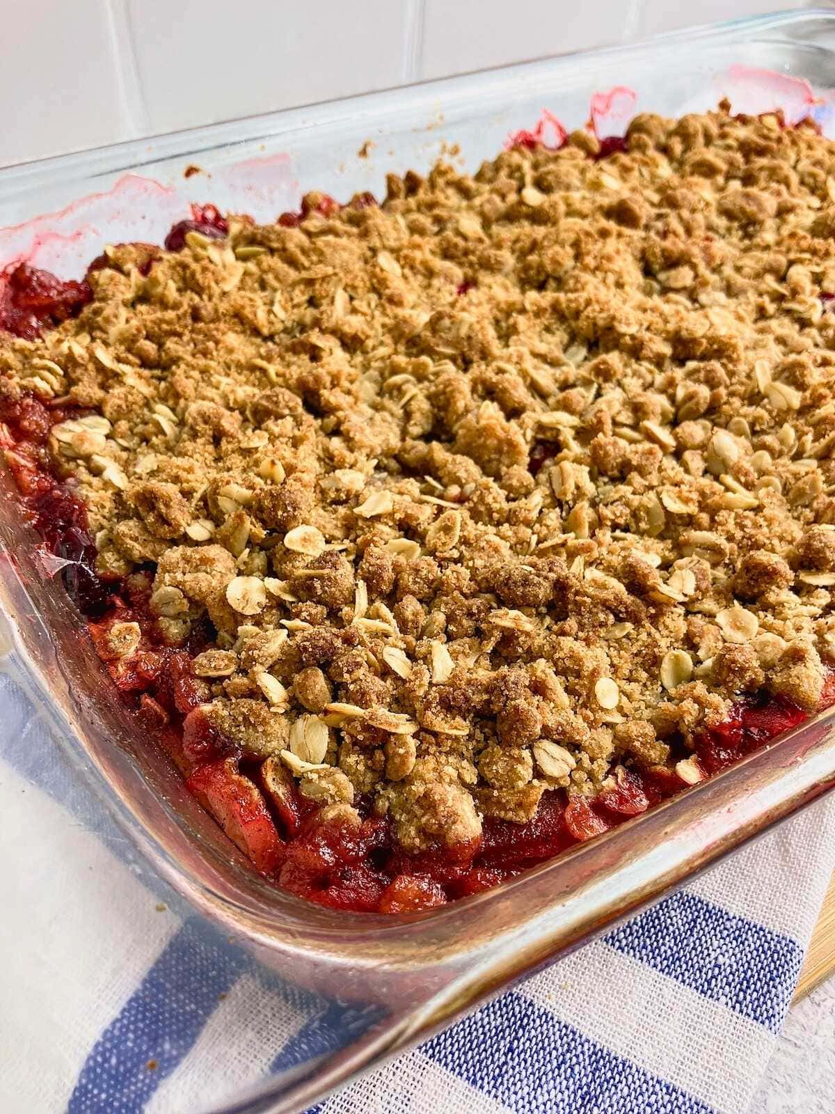 A glass 9x13 baking dish of warm apple cranberry crisp.