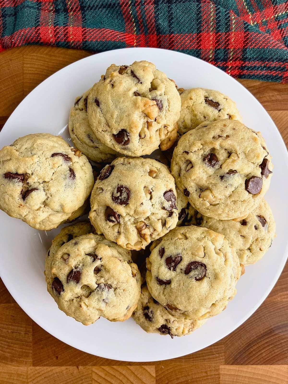 A plate of stacked chocolate chip walnut cookies.