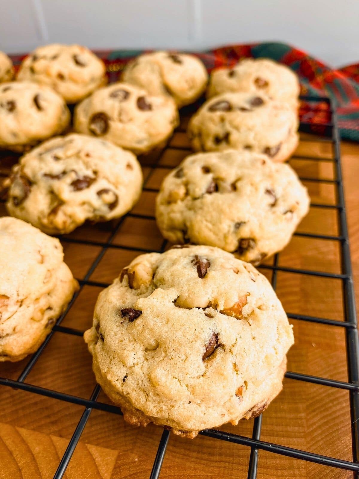 Hot homemade chocolate chip and walnut cookies are cooling on a wire rack.