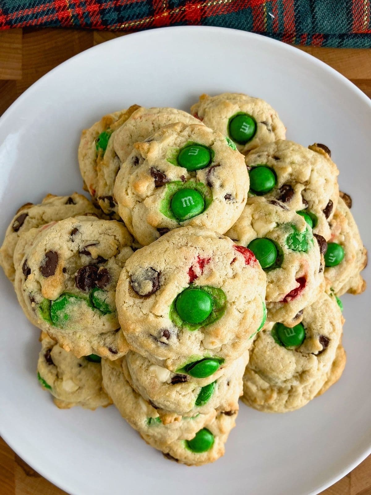 Christmas chocolate chip cookies with green and red M&Ms on a white platter.