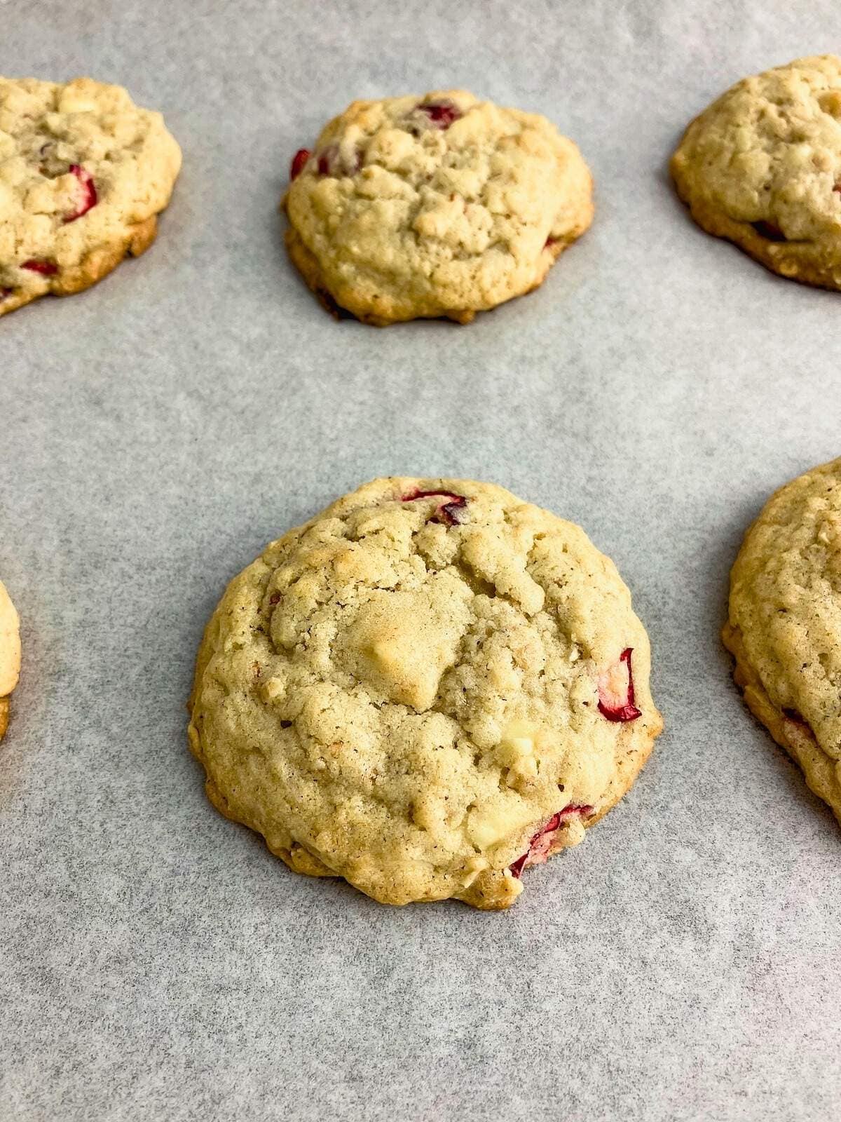 Baked oatmeal cookies with cranberries and white chocolate on the baking sheet.