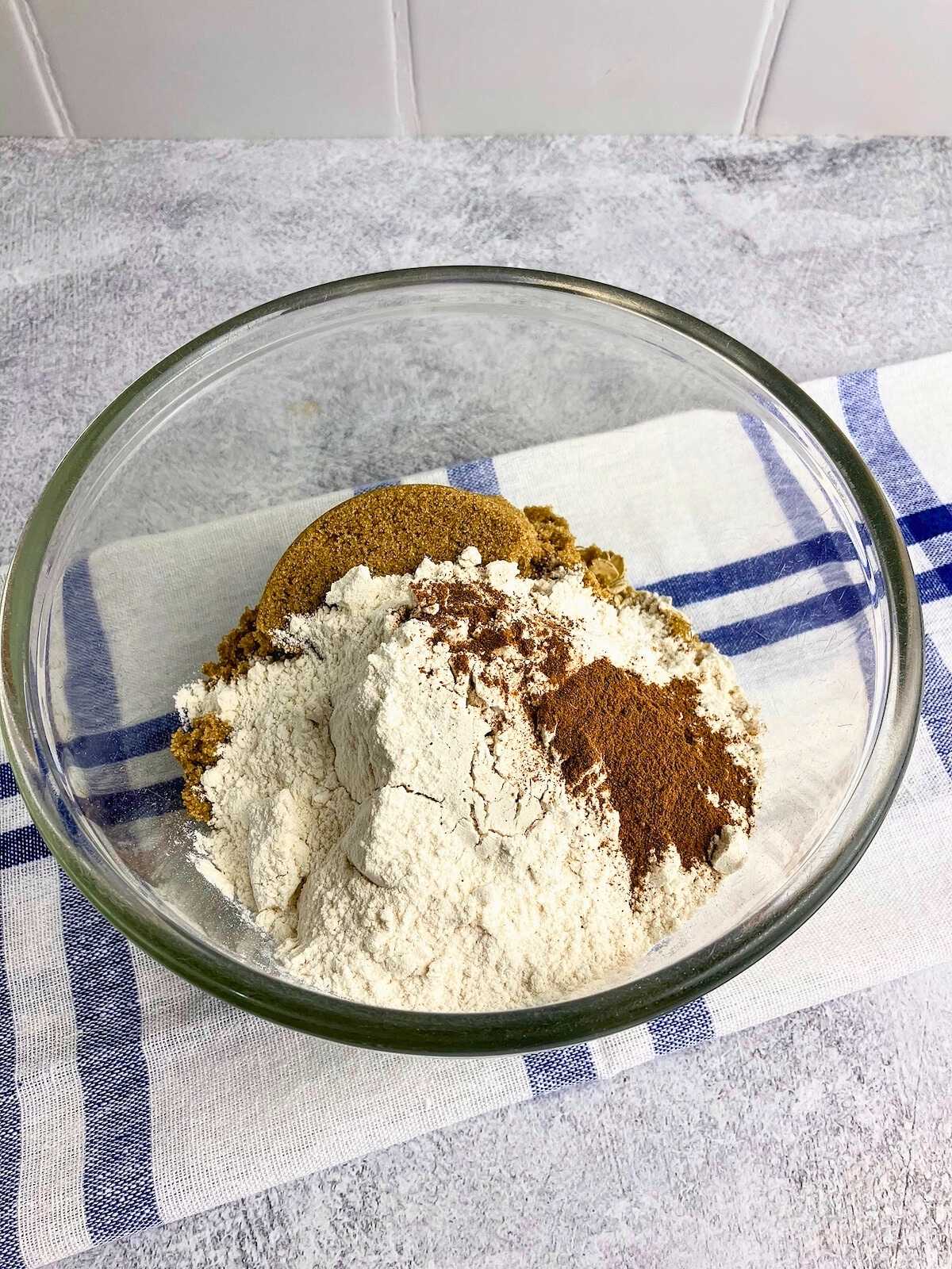 Flour, brown sugar, rolled oats, and cinnamon in a mixing bowl.
