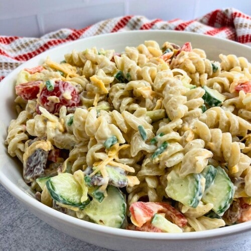 Creamy bacon pasta salad with cheese and veggies in a large bowl.