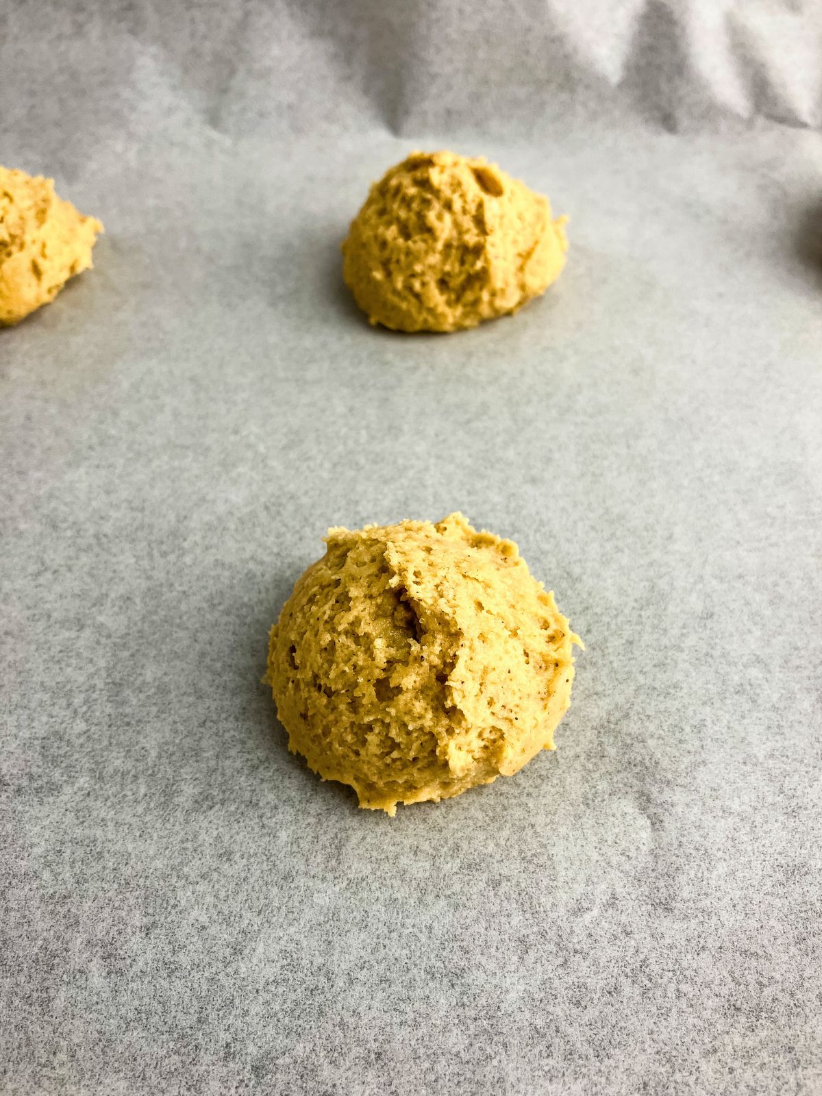 Eggnog cookie dough balls on a parchment-lined baking sheet.