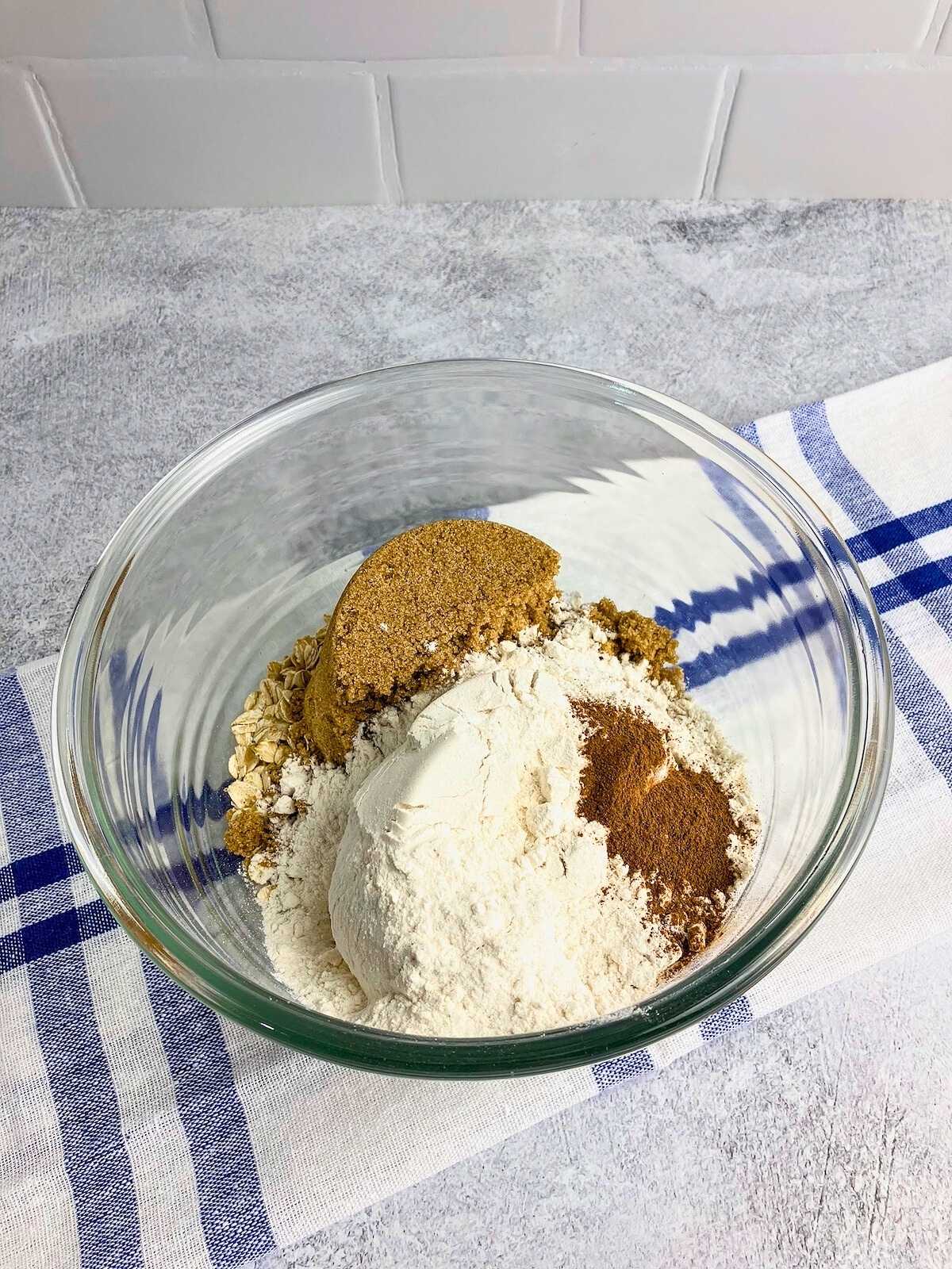 A mixing bowl with flour, oats, brown sugar, and spices.