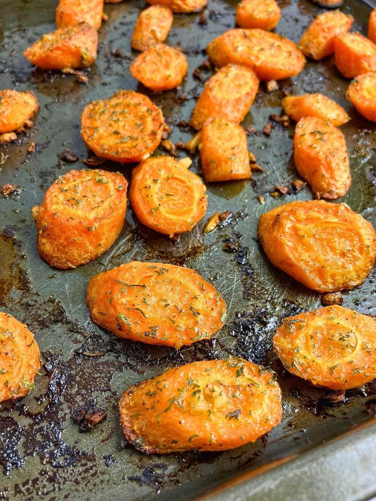 Roasted sliced garlic carrots on a baking sheet.