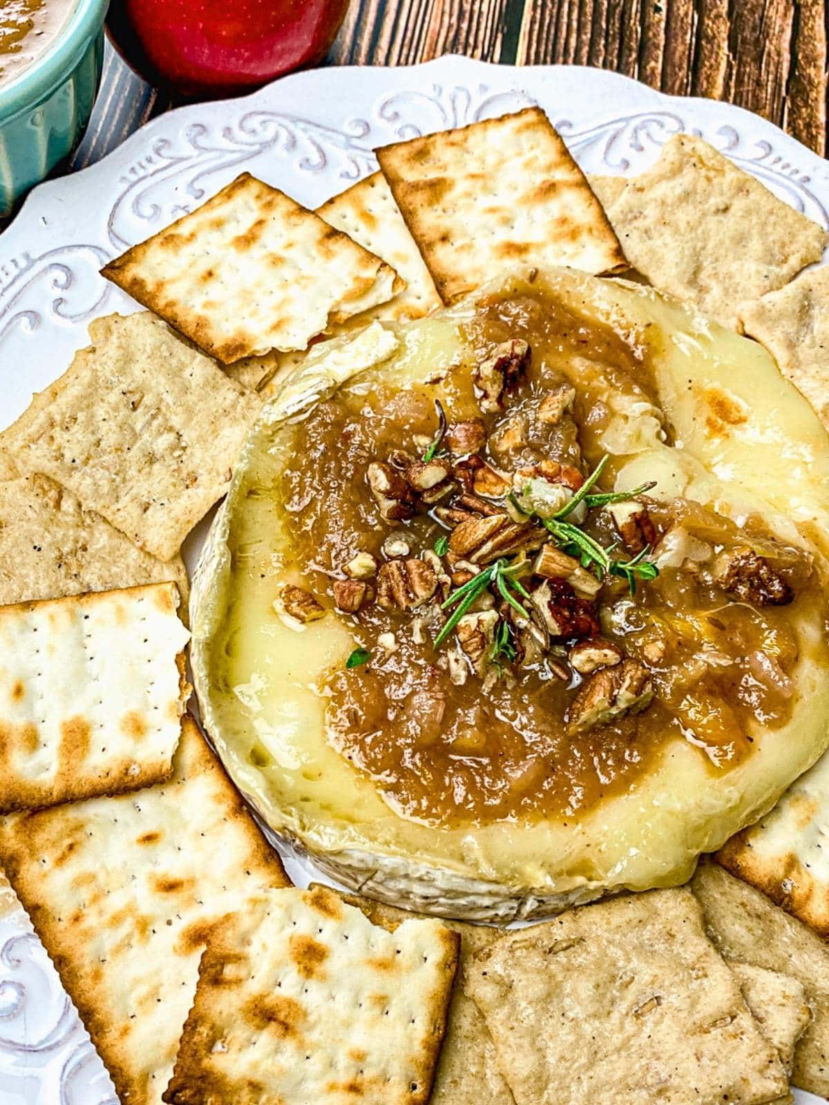 Baked brie with pecan and apple topping with crackers.