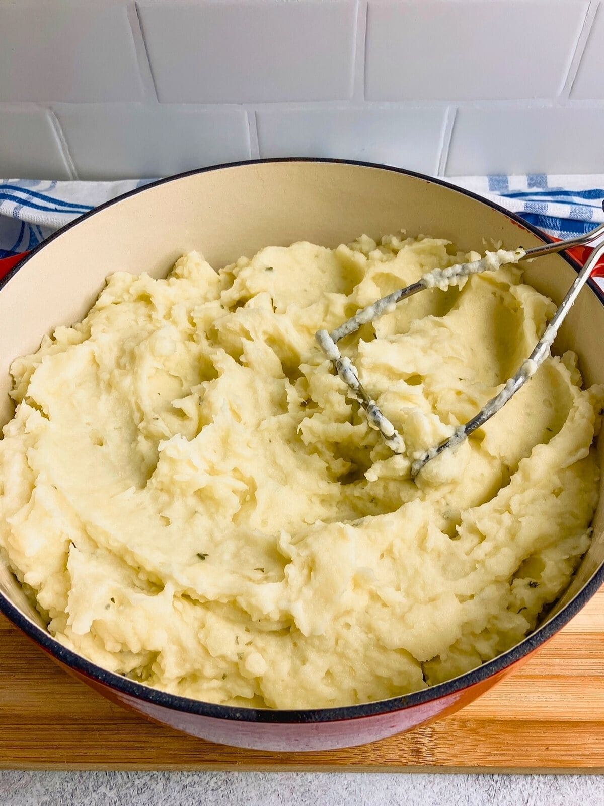 Mashing cooked potatoes with a potato masher.