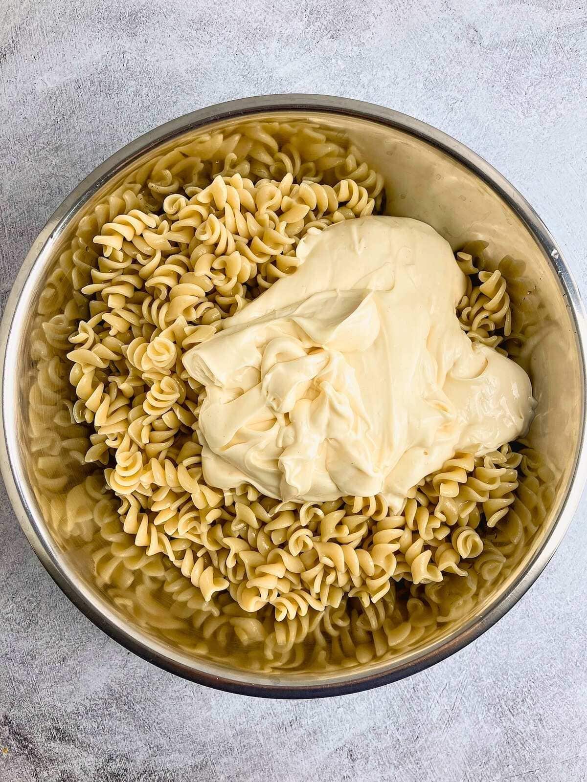 Mayo was added to the cooked pasta in a large mixing bowl.