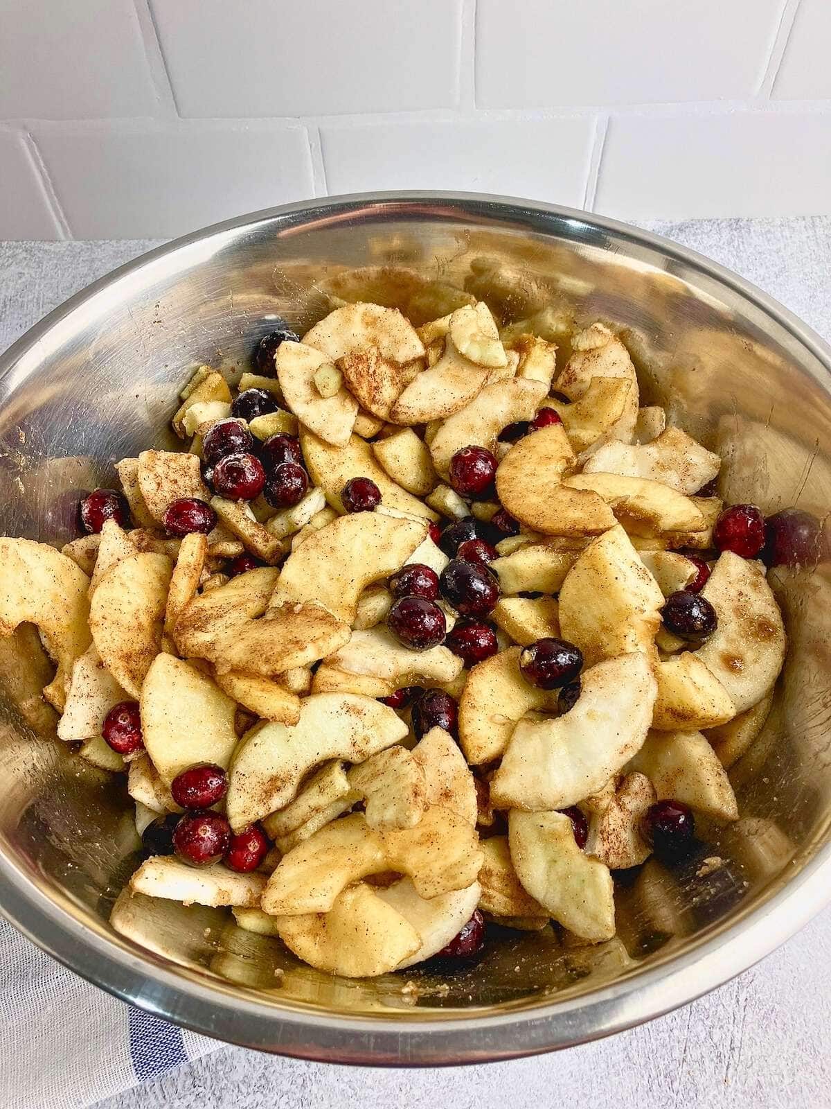 Sliced apples and cranberries mixed with sugar and spices.