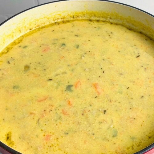 Homemade pumpkin vegetable soup with pork in a large red dutch oven.