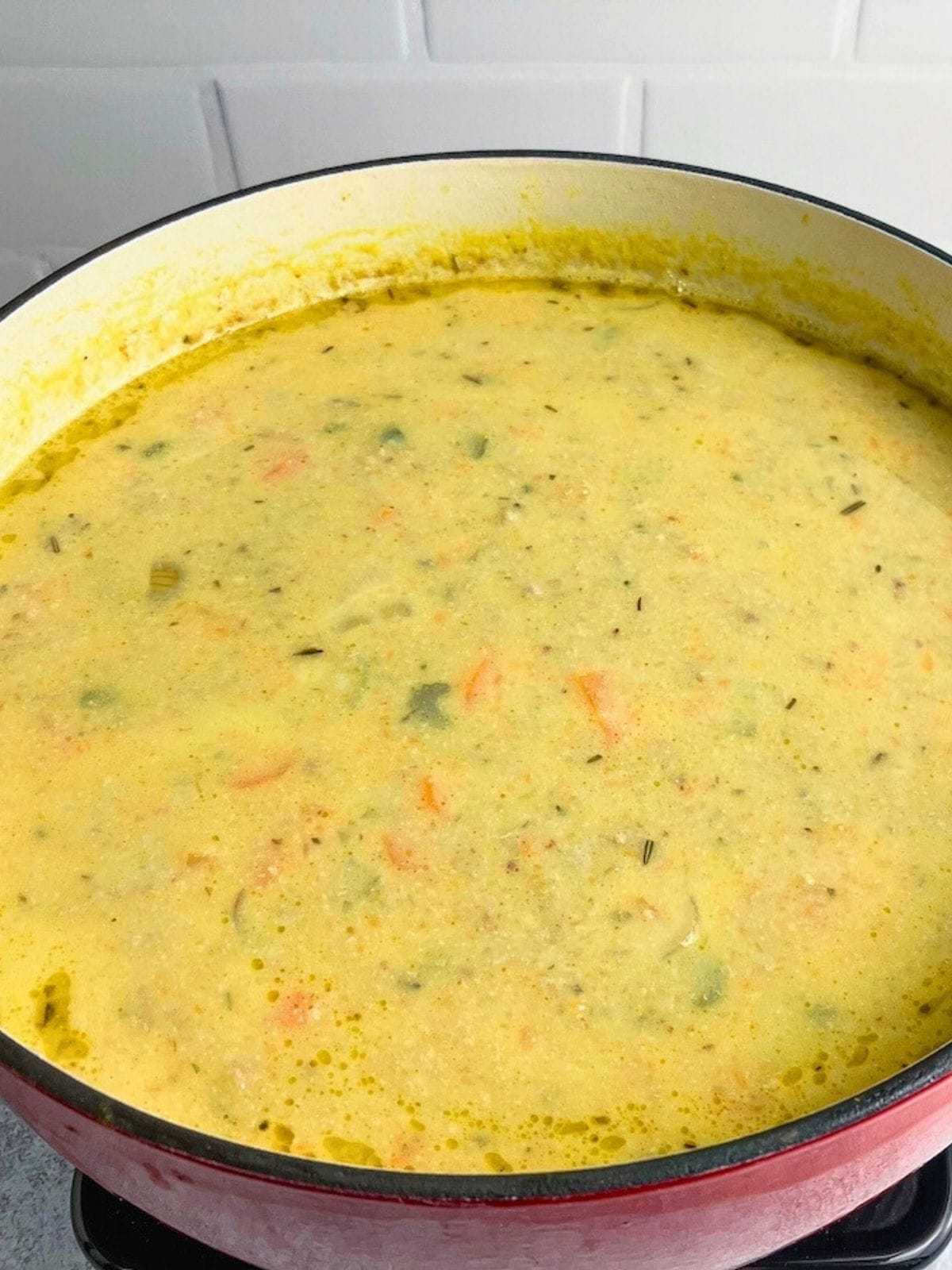 Homemade pumpkin vegetable soup with pork in a large red dutch oven.