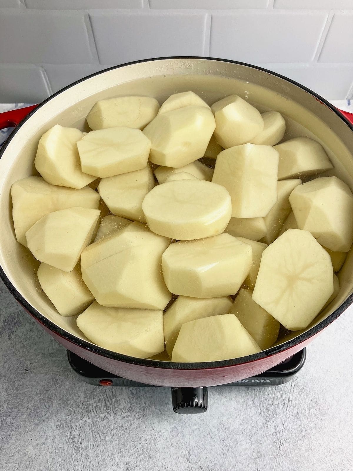 A large pot of peeled and quartered potatoes covered in water.