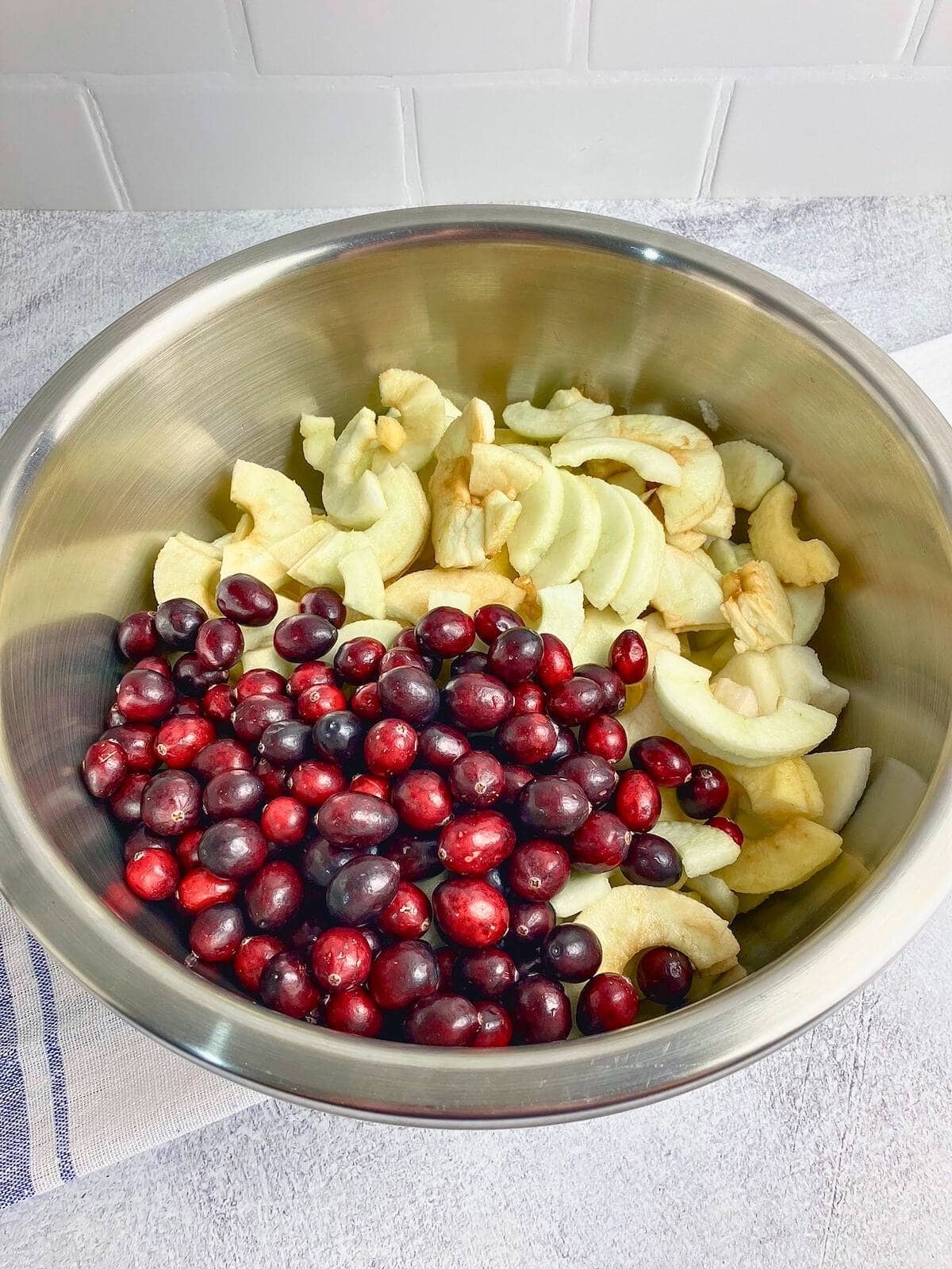 Sliced apples and cranberries in a large mixing bowl.