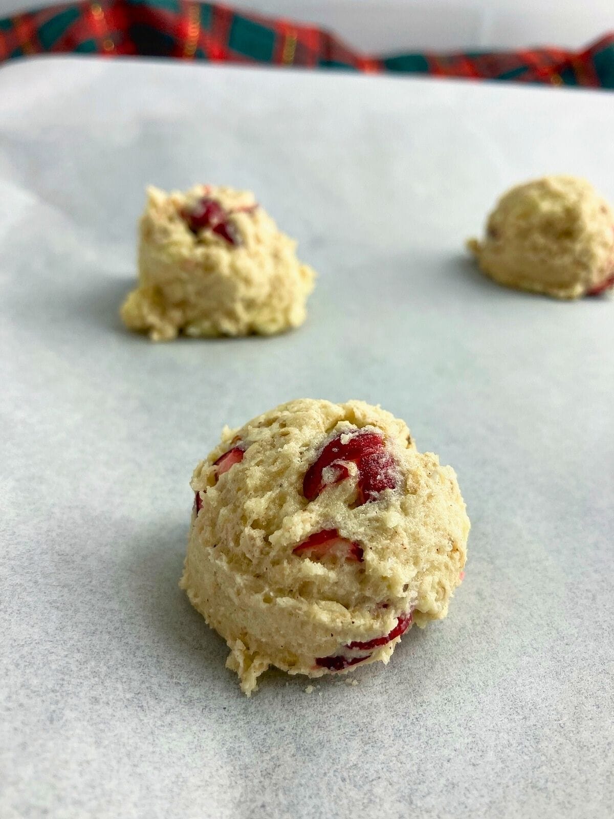 Cookie dough balls on a parchment lined baking sheet.