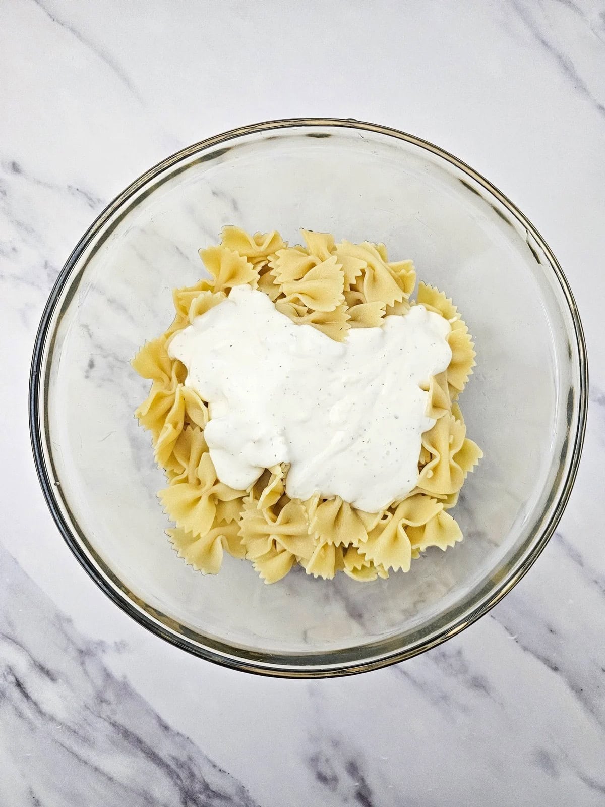 Ranch dressing was added to the bowl of pasta.