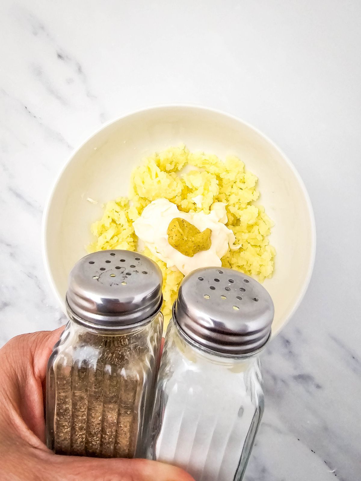 Holding salt and pepper shakers to add seasoning to the filling.