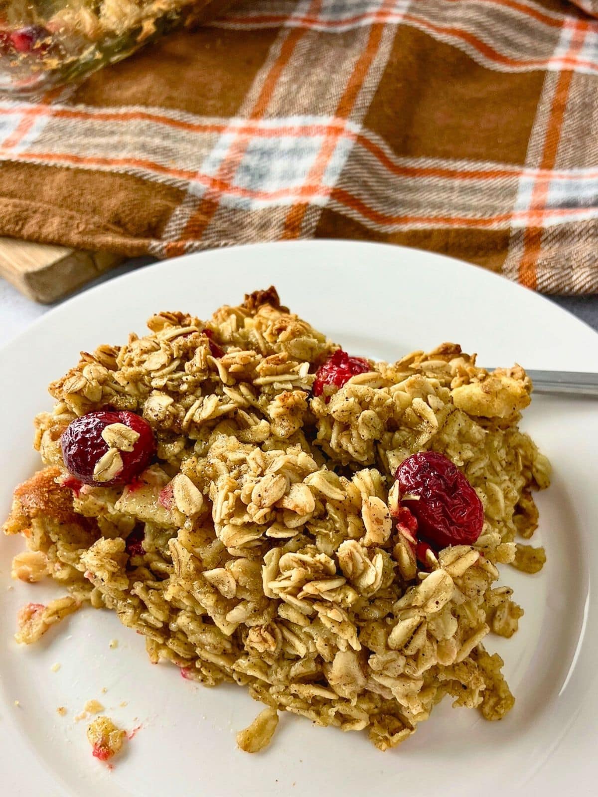 A slice of apple cranberry baked oatmeal on a white plate.