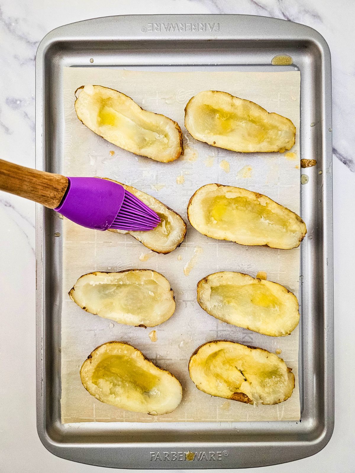 Basting the hollowed-out potatoes with the melted butter mixture.