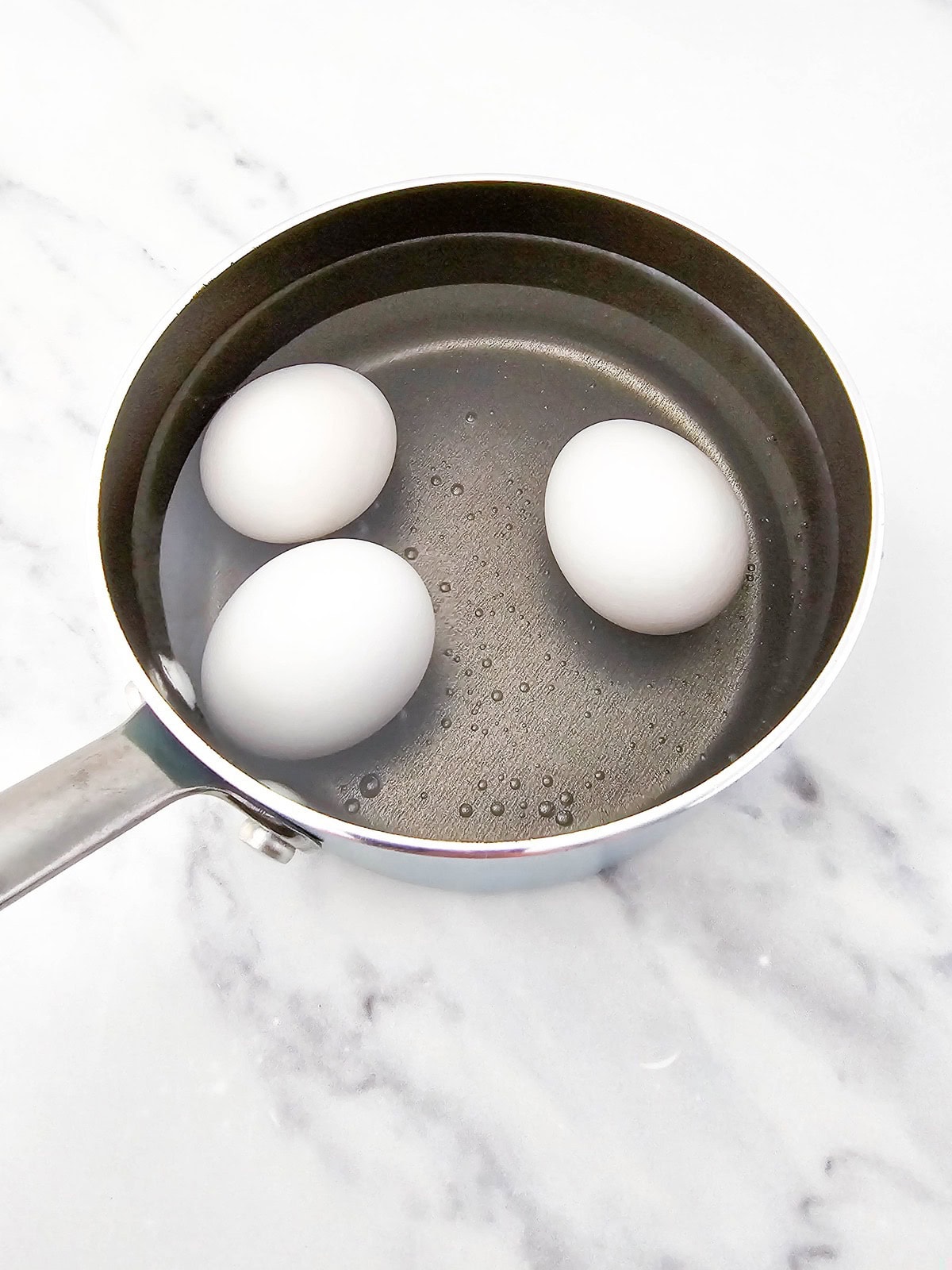 Three eggs in a pot of water.